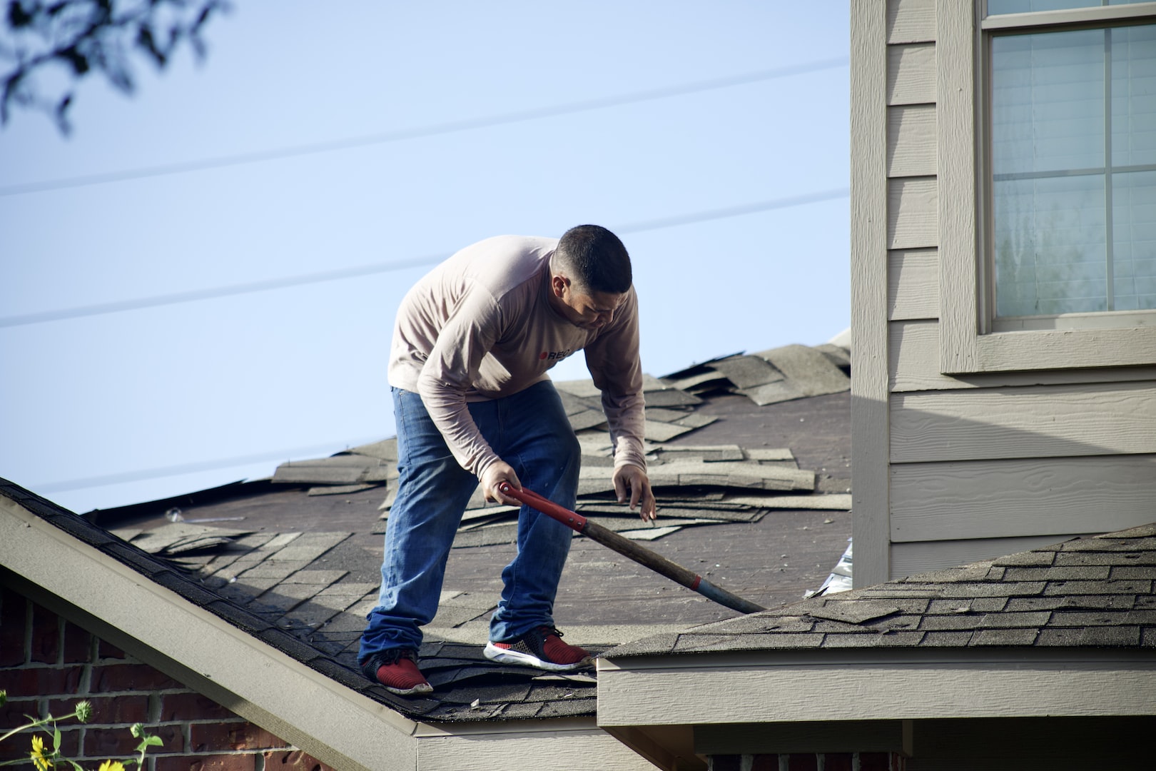 Man on roof removing asbestos tiles.